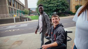 Amputee male in wheel chair on street with friends