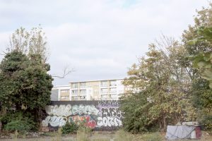 Council housing block viewed from abandoned lot with graffiti wall