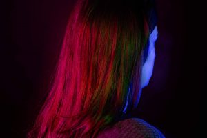 Woman facing away from camera bathed in coloured light