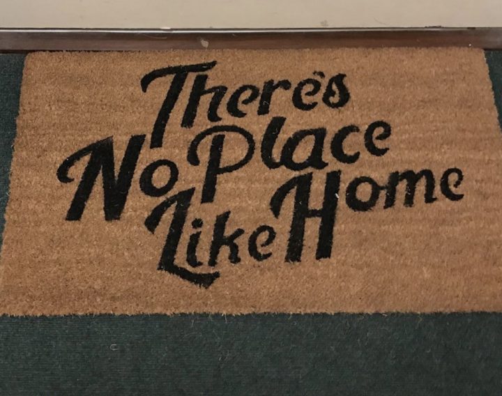 a photograph of a doormat with the text 'There's No Place Like Home' on it