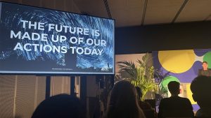 photo of Dr Leyla Acaroglu speaking at Design for Planet with a large screen showing the text 'The future is made up of our actions today'