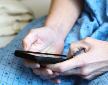 a person in a hospital gown holding a mobile phone