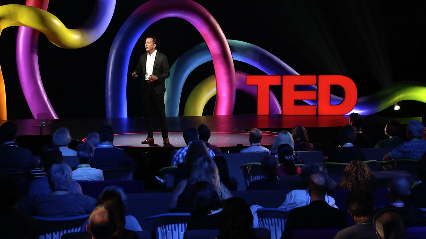 Jamil Zaki onstage with the TED talks logo behind him